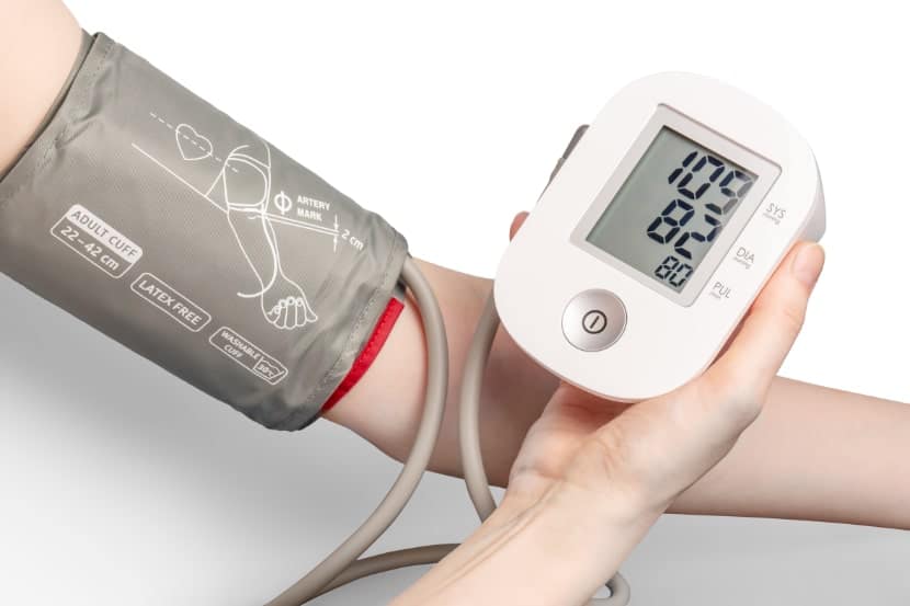 Blutdruckmessgerät mit Händen auf weißem Hintergrund