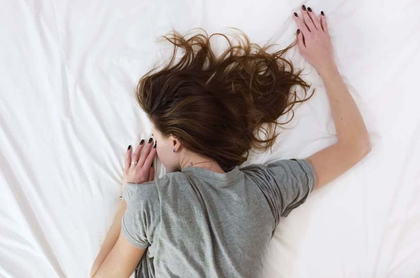 Frau liegt erschöpft auf dem Bett, Energiemangel, Müdigkeit, Lethargisch