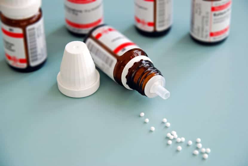 Nahaufnahme von homöopathischen Globuli alternativer Medizin auf grüner Oberfläche