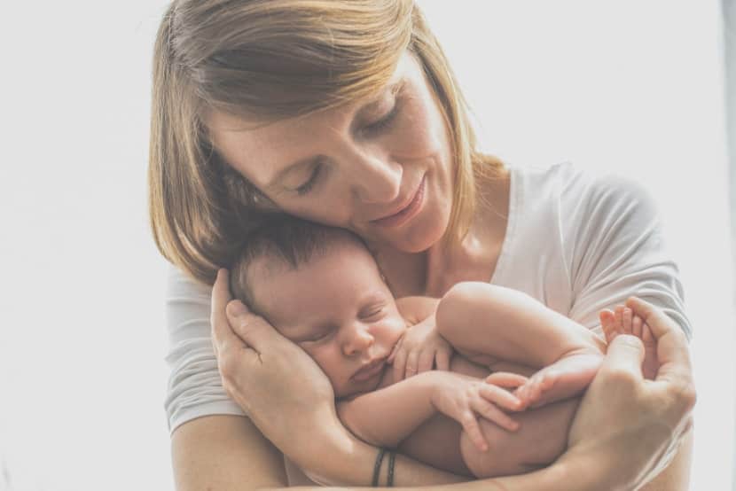 Frau mit Wochenfluss trägt Baby