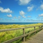 Holzsteg auf Sylt im Herbst mit Strandblick, blauem Himmel und Schleierwolken